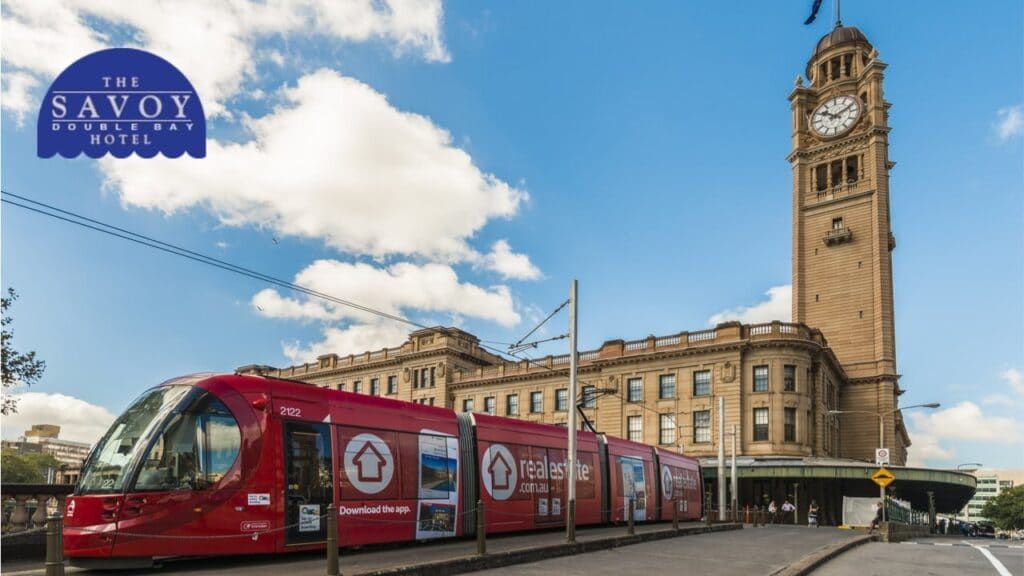 Best Way to Get Around Sydney - Sydney A red light rail tram passing in front of the historic, stone-faced Sydney Central Station building.