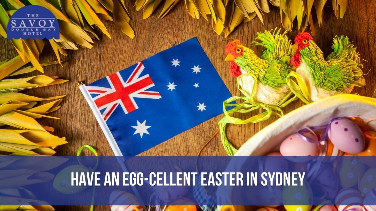 An Australian flag, a basket of colourful Easter eggs, and decorative rooster figurines on a wooden surface