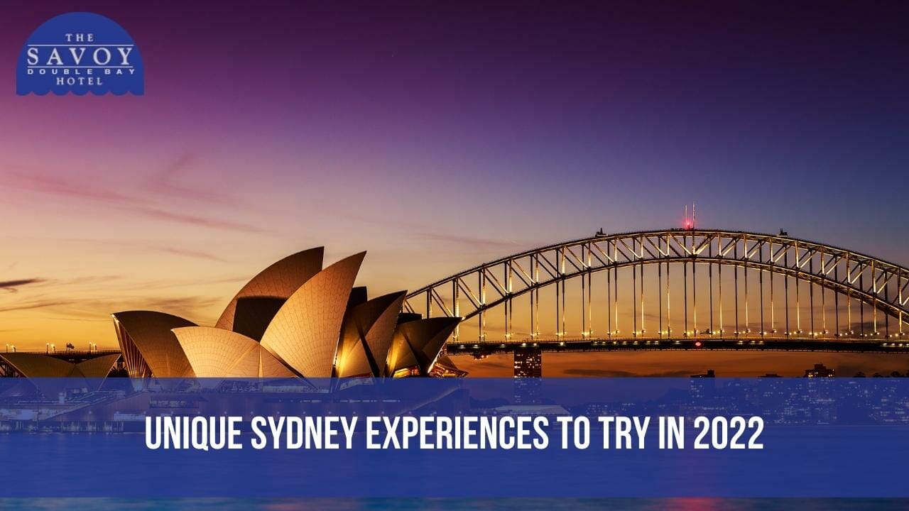 The Sydney Opera House and Sydney Harbour Bridge illuminated at sunset against a purple and orange sky.