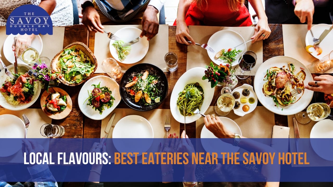 An overhead view of a group of people dining around a wooden table covered with various dishes, salads, and wine glasses.