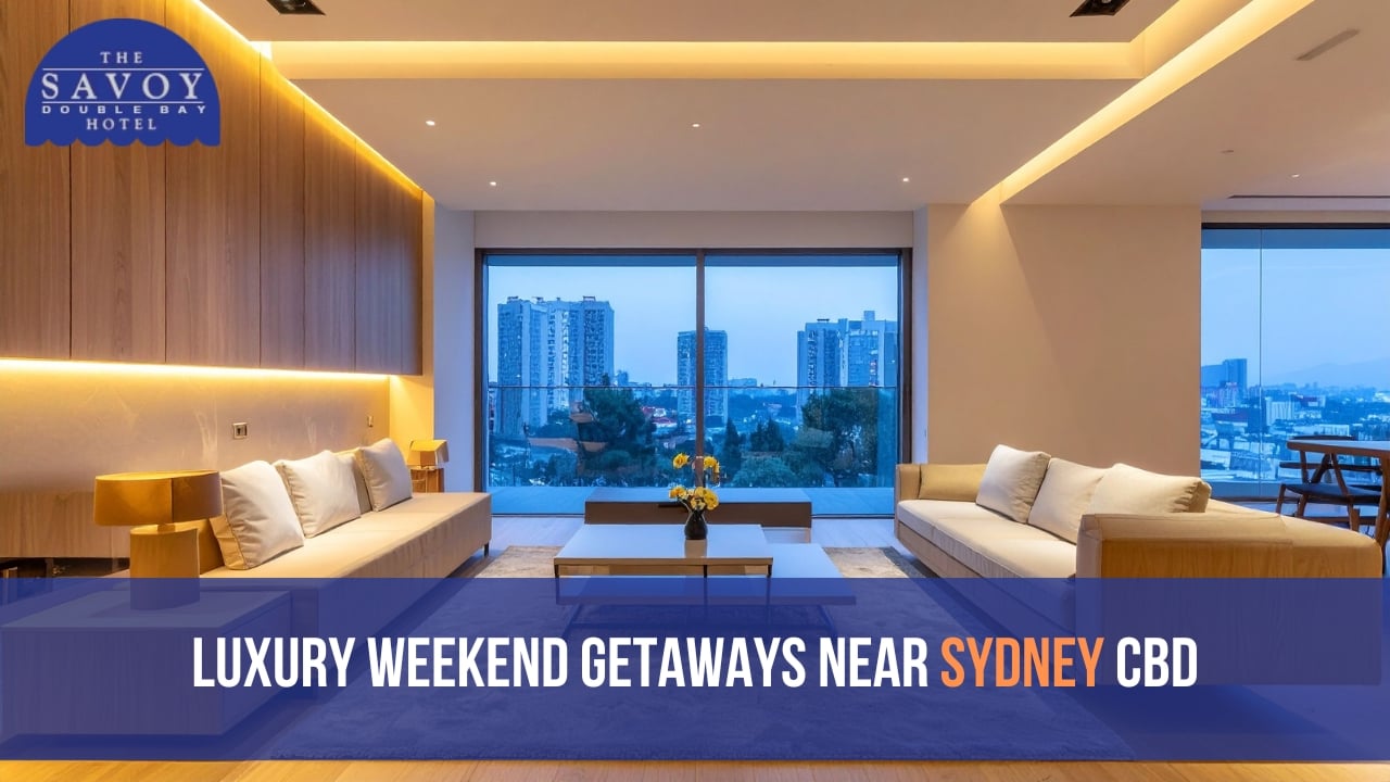 A luxurious, modern apartment living room with plush cream sofas, recessed warm lighting, and a large sliding glass door offering a twilight city view