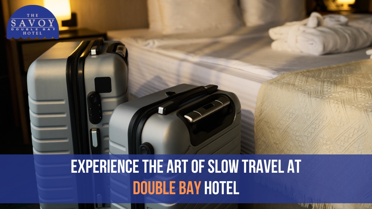 Two silver hardshell suitcases sit on the floor next to a hotel bed in Double Bay.