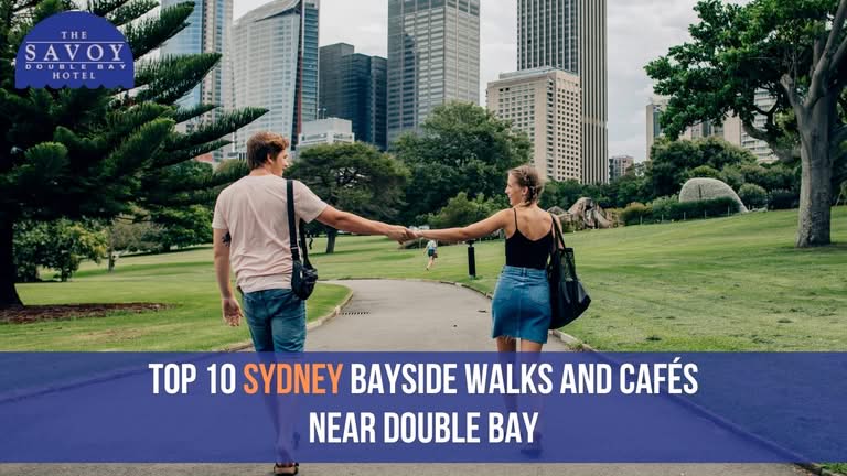 A couple holding hands while walking along a park path in front of the Sydney city skyline.